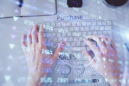Double exposure of man's hands typing over laptop keyboard and forex chart hologram drawing. Top...