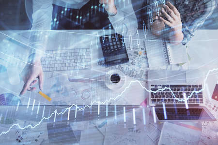 Double exposure of man and woman working together and financial graph hologram drawing. market analysis concept. Computer background. Top View.の写真素材