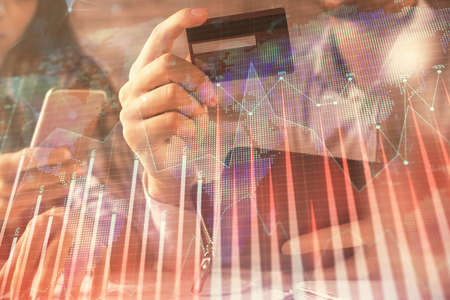 Double exposure of man and woman on-line shopping holding a credit card and forex graph hologram...