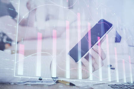 Double exposure of man's hands holding and using a digital device and forex graph drawing. Financial market concept.の写真素材