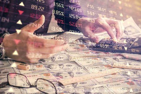 Double exposure of man's hands holding and using a digital device and forex graph drawing. Financial...