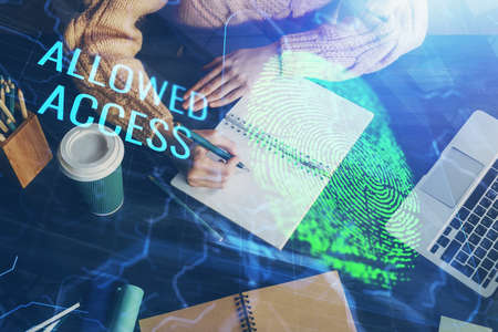 Blue fingerprint hologram over hands taking notes background. Concept of security. Double exposure