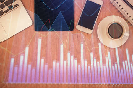 Double exposure of financial chart hologram over desktop with phone. Top view. Mobile trade platform concept.の写真素材