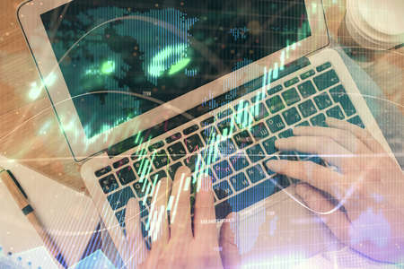 Double exposure of mans hands typing over computer keyboard and forex graph hologram drawing. Top view. Financial markets concept.の写真素材
