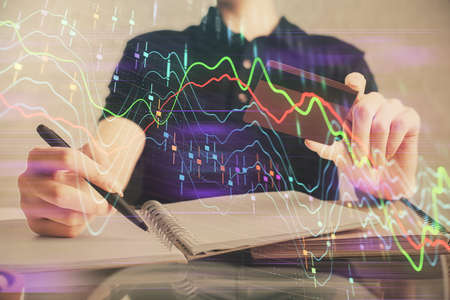 Double exposure of man hands holding a credit card and Forex graph drawing. Stock trading and...