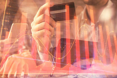 Double exposure of man and woman on-line shopping holding a credit card and forex graph hologram drawing. Stock market E-commerce pay on-line concept.の写真素材