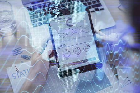 Double exposure of mans hands holding and using a digital device and forex graph drawing. Financial...