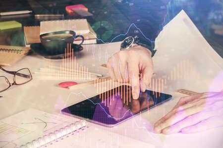 Double exposure of mans hands holding and using a digital device and forex graph drawing. Financial market concept.の写真素材
