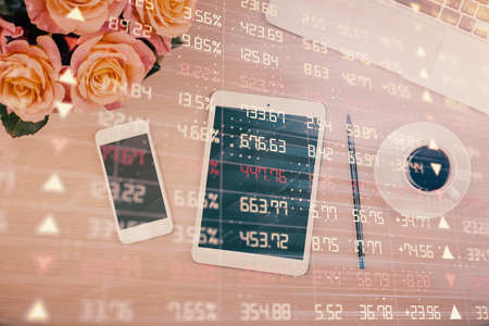 Double exposure of forex graph hologram over desktop with phone. Top view. Mobile trade platform...