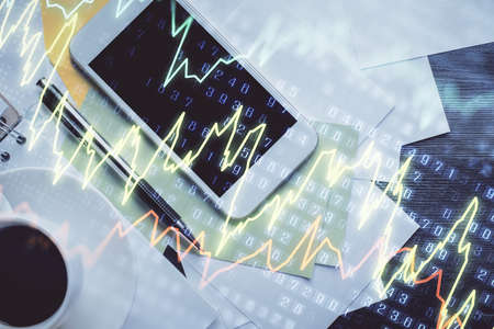 Multi exposure of forex graph hologram over desktop with phone. Top view. Mobile trade platform...