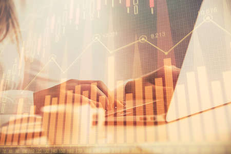 Double exposure of woman hands working on computer and forex graph hologram drawing. Financial...