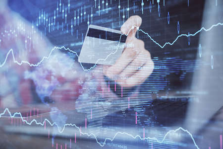 Double exposure of man hands holding a credit card and Forex graph drawing. Stock trading and...
