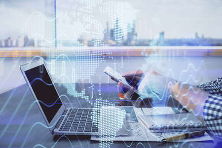 Double exposure of mans hands holding and using a digital device and forex graph drawing. Financial market concept.の写真素材