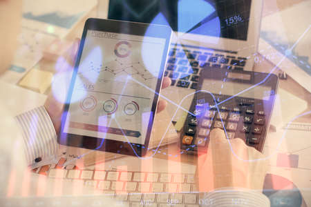 Double exposure of mans hands holding and using a digital device and forex graph drawing. Financial...