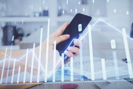 Double exposure of mans hands holding and using a digital device and forex graph drawing. Financial market concept.の写真素材