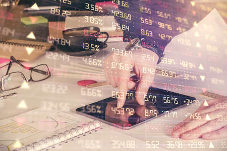 Double exposure of mans hands holding and using a digital device and forex graph drawing. Financial...