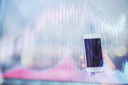 Double exposure of forex chart sketch hologram and woman holding and using a mobile device. Stock market concept.の写真素材