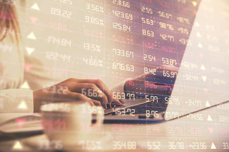 Double exposure of woman hands working on computer and forex graph hologram drawing. Financial...