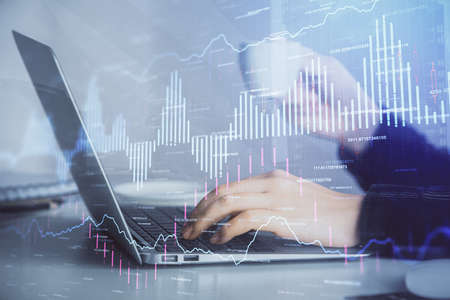 Double exposure of businesswoman hands typing on computer and forex graph hologram drawing....
