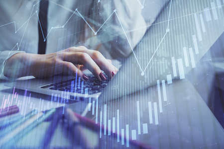 Double exposure of woman hands typing on computer and financial graph hologram drawing. Stock market...