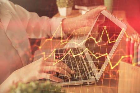 Double exposure of woman hands typing on computer and forex chart hologram drawing. Stock market invest concept.の写真素材