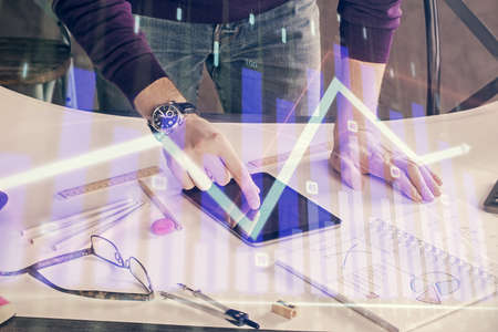 Double exposure of mans hands holding and using a digital device and forex graph drawing. Financial...