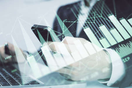 Multi exposure of mans hands holding and using a digital phone and forex graph drawing. Financial...