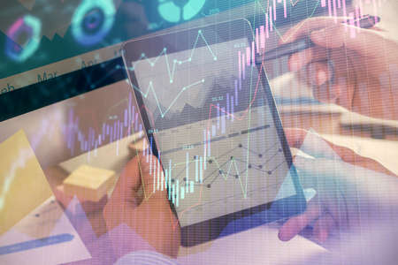 Double exposure of mans hands holding and using a phone and financial chart drawing. Market analysis concept.の写真素材