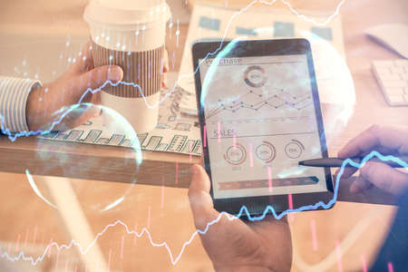 Double exposure of mans hands holding and using a phone and financial chart drawing. Market analysis...