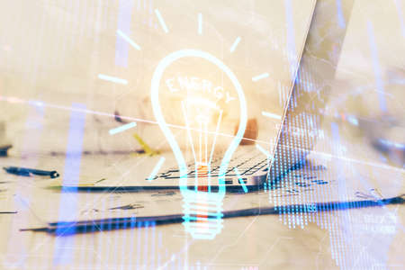 Computer on desktop in office with bulb icon hologram. Double exposure. Concept of idea.の写真素材