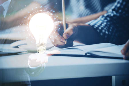 View of Bulb lamp idea concept icon on a futuristic interface with writing mans hand background....