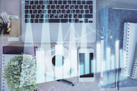 Double exposure of financial graph hologram over desktop with phone. Top view. Mobile trade platform concept.の写真素材
