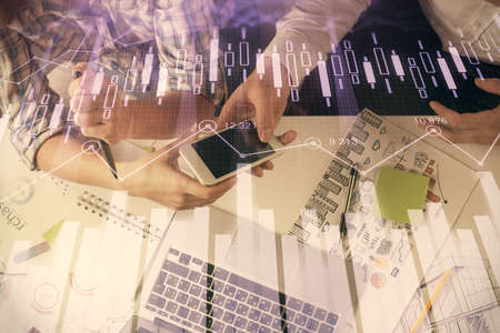 Double exposure of forex graph drawing and man and woman working together holding and using a mobile...