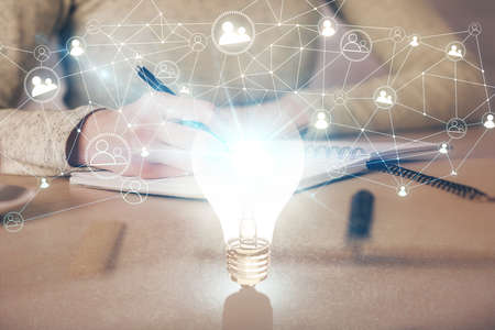 Bulb hologram over hands taking notes background. Concept of idea. Double exposureの写真素材
