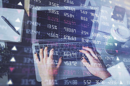 Double exposure of woman hands typing on computer and forex chart hologram drawing. Stock market...