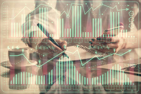 Double exposure of financial graph sketch hologram and woman holding and using a mobile device....