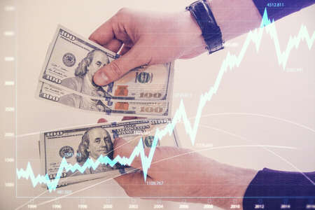 Multi exposure of financial graph drawing hologram and USA dollars bills and man hands. Analysis concept.の写真素材