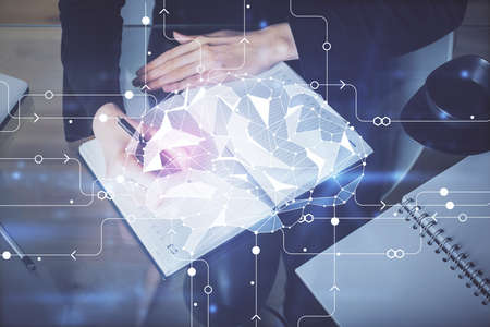 Double exposure of writing hand on background with brain hologram. Concept of learning.