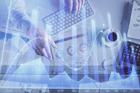 Multi exposure of mans hands typing over computer keyboard and forex graph hologram drawing. Top...