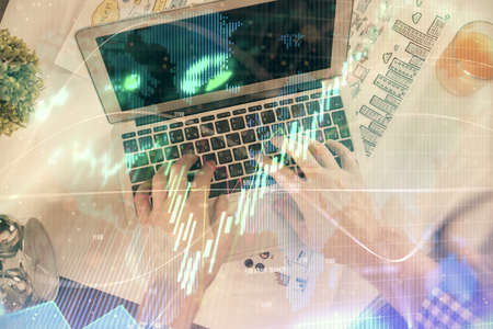 Double exposure of mans hands typing over laptop keyboard and forex chart hologram drawing. Top...