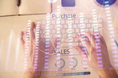 Double exposure of mans hands typing over laptop keyboard and forex chart hologram drawing. Top view. Financial markets concept.の写真素材