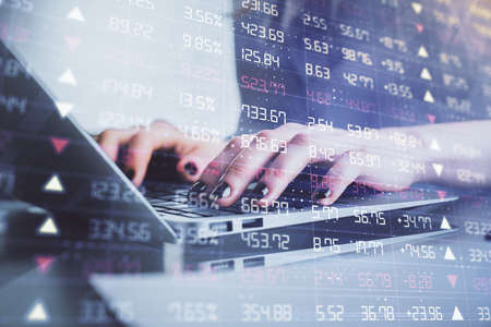 Double exposure of woman hands typing on computer and forex chart hologram drawing. Stock market...