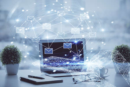 Desktop computer background in office and flying envelops hologram drawing. Double exposure. Electronic mail concept.の写真素材