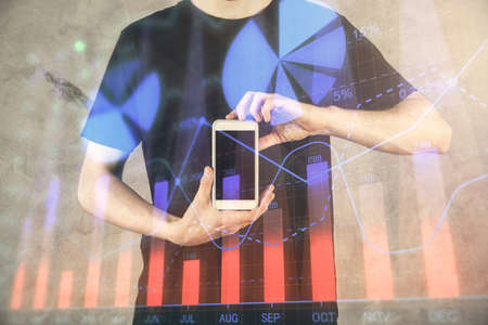 Double exposure of mans hands holding and using a digital device and forex graph drawing. Financial market concept.の写真素材
