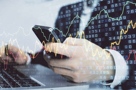 Multi exposure of mans hands holding and using a digital phone and forex graph drawing. Financial...