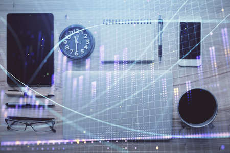 Double exposure of forex graph hologram over desktop with phone. Top view. Mobile trade platform concept.の写真素材