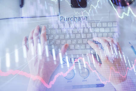 Double exposure of mans hands typing over laptop keyboard and forex chart hologram drawing. Top...