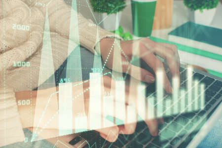 Double exposure of woman hands typing on computer and forex chart hologram drawing. Stock market...