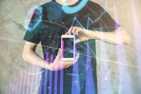 Double exposure of mans hands holding and using a digital device and forex graph drawing. Financial...