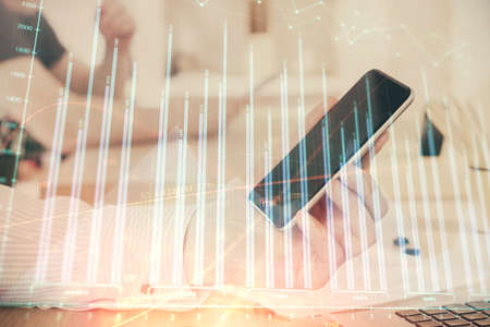 Double exposure of mans hands holding and using a digital device and forex graph drawing. Financial market concept.の写真素材